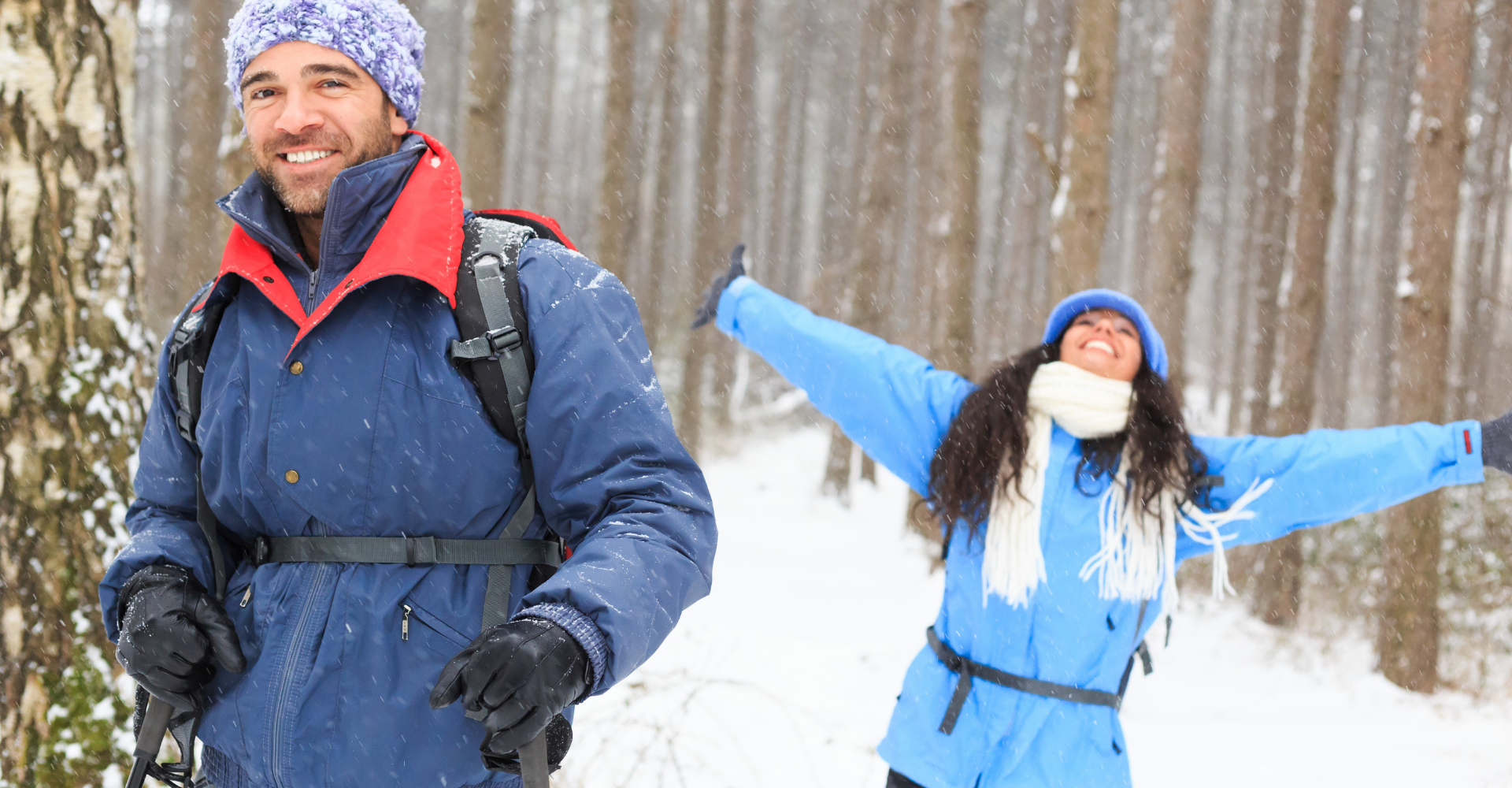 happy young white couple cross country skiing in the woods